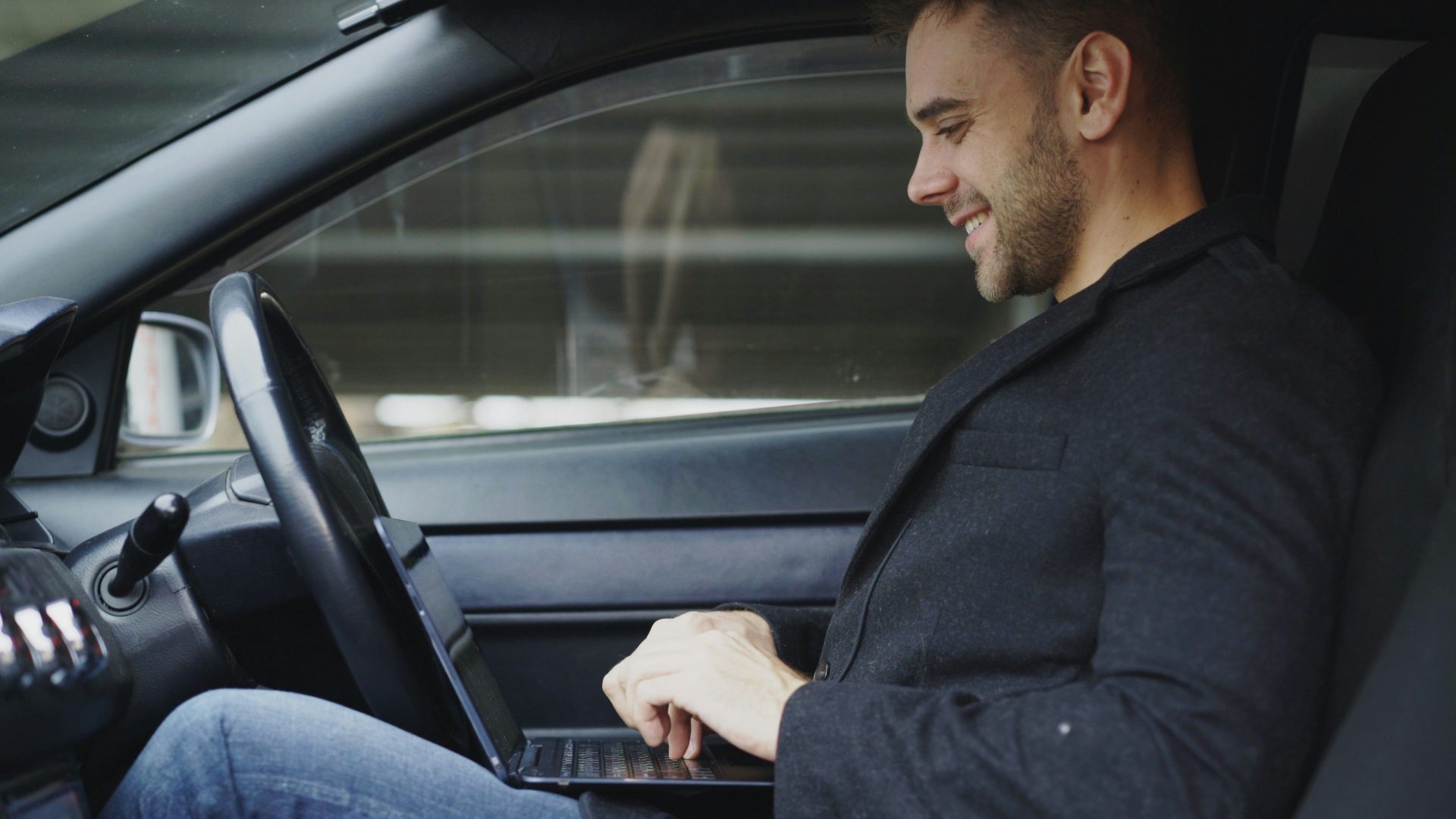 Mann arbeitet in einem Auto an einem Laptop