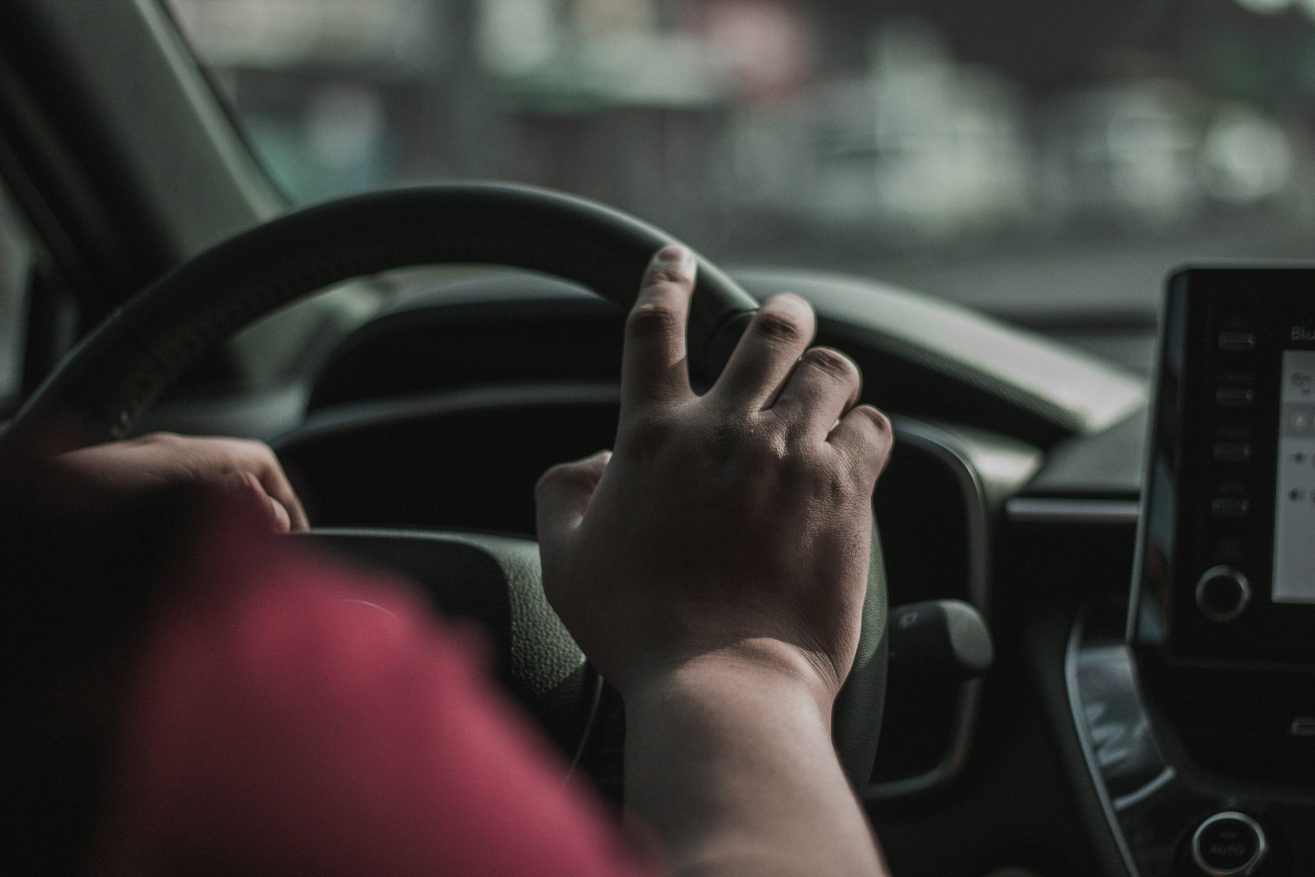 eine Person, die ein Auto fährt und die Hand am Lenkrad hat